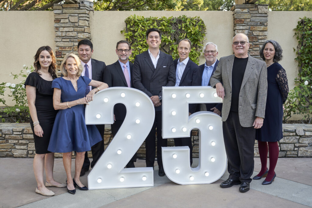 IEA Board of Directors standing behind a 25 marquee light sign at the 25th Anniversary Celebration Gala