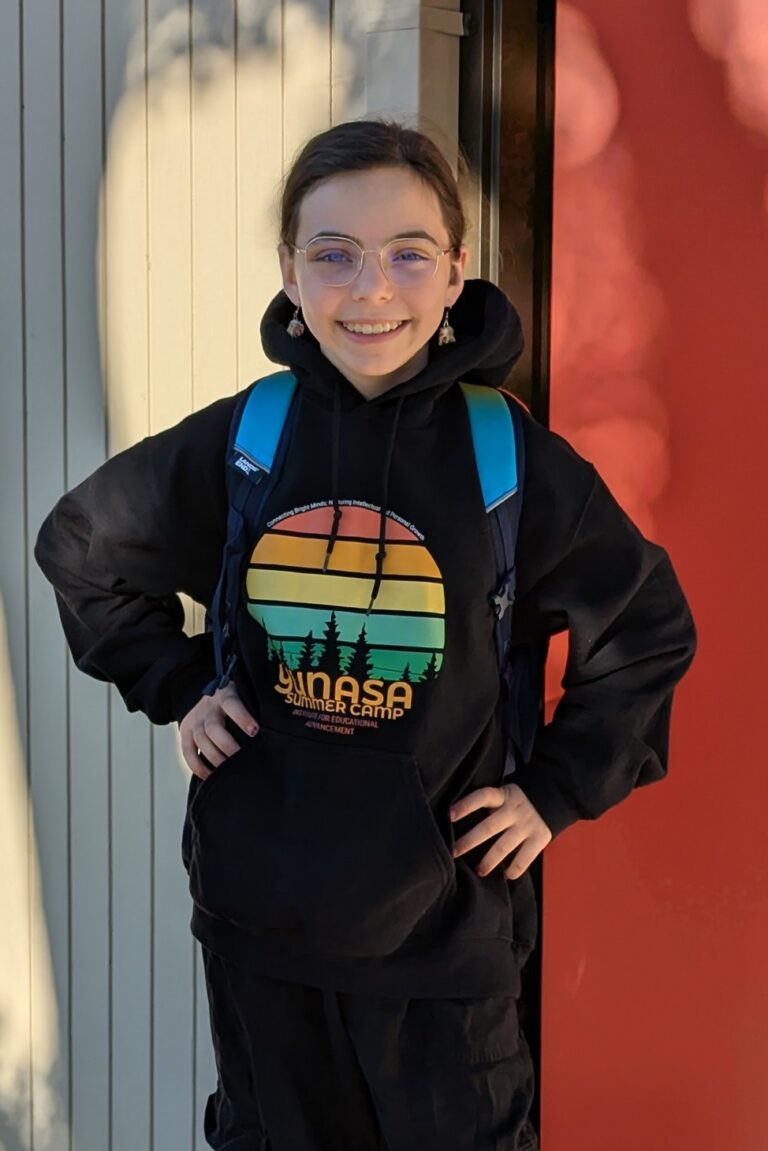 Young teenage girl wearing a Yunasa hoodie and black pants posing with her hands on her hips