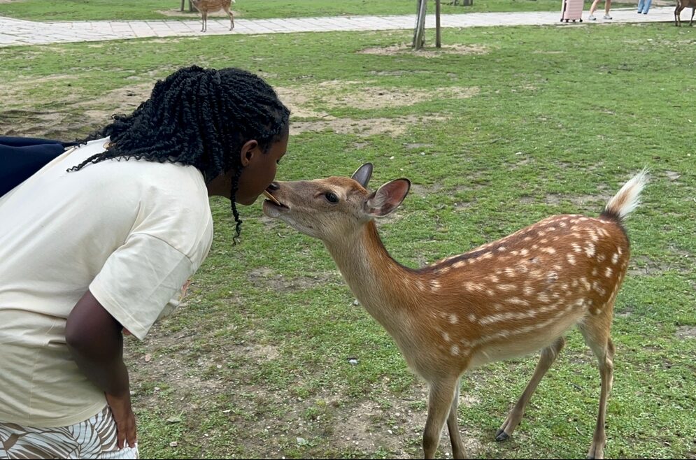 Daryn bent over a lawn kissing a fawn